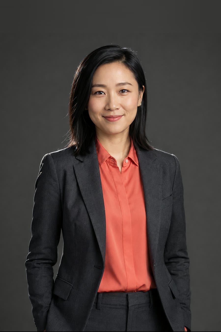 Mei Chen, design lead — a woman in a charcoal trouser suit and coral blouse